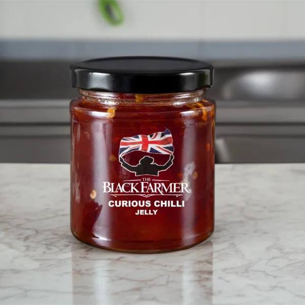 A jar of The Black Farmer’s Curious Chilli Jelly, showing a deep red jelly with a subtle chilli pepper design.