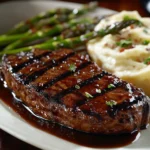 beef sirloin steak glazed with a sticky barbecue sauce, grilled to a perfect char with visible grill marks, served with a side of garlic mashed potatoes and grilled asparagus