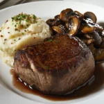 premium aged fillet steak, perfectly seared with a tender, melt-in-the-mouth texture, served on a white plate with a side of truffle mashed potatoes and sautéed wild mushrooms