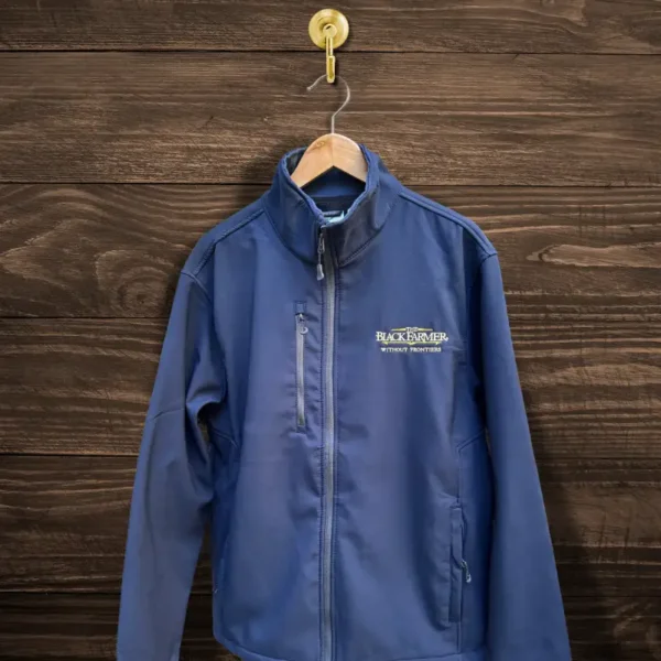 The Black Farmer Softshell Jacket in navy blue, featuring a sleek design with a zip closure and embroidered logo, displayed on a wooden hanger.